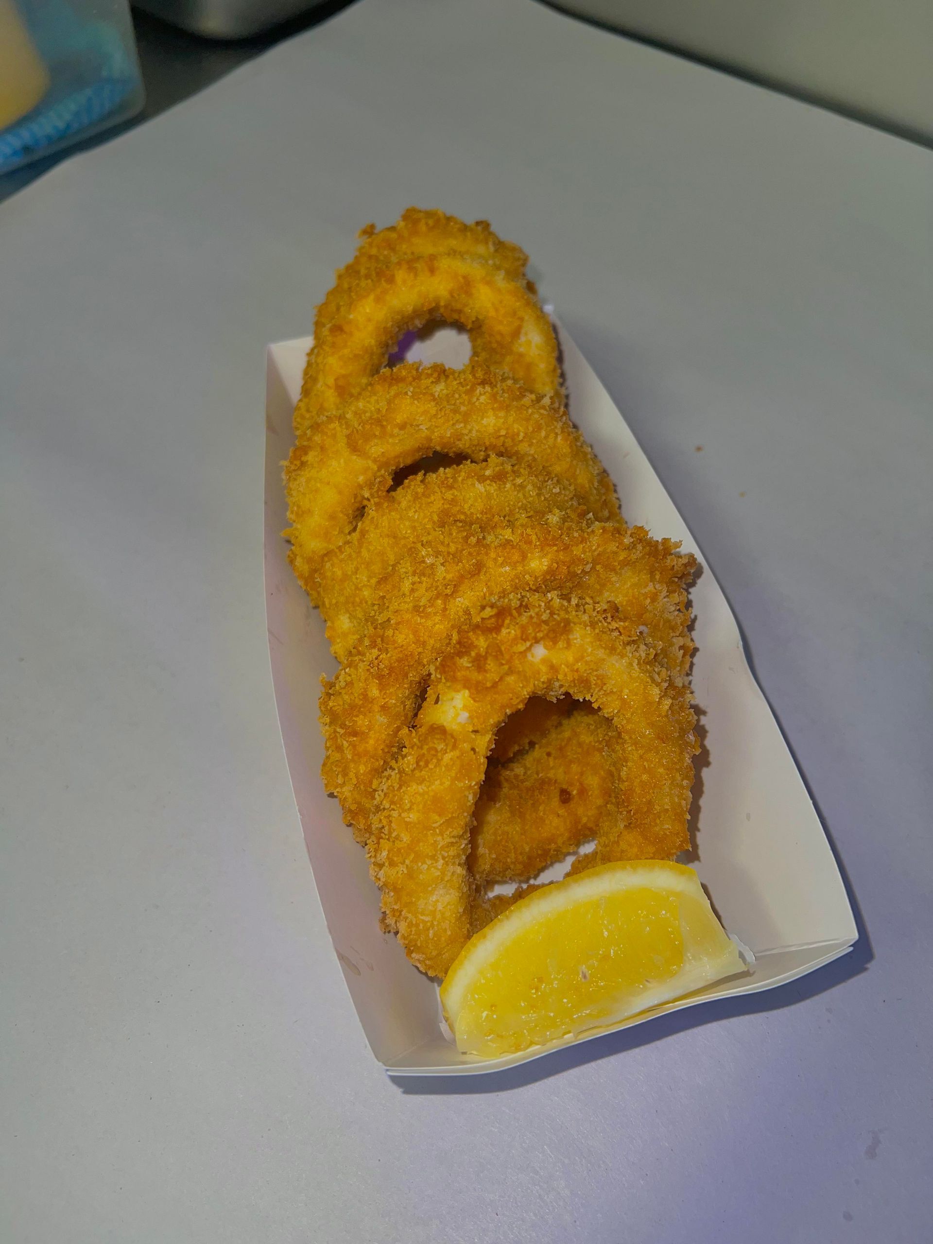 Fried calamari rings with a lemon wedge in a paper container. — Boundary Street Fish & Burger Bar in Railway Estate, QLD