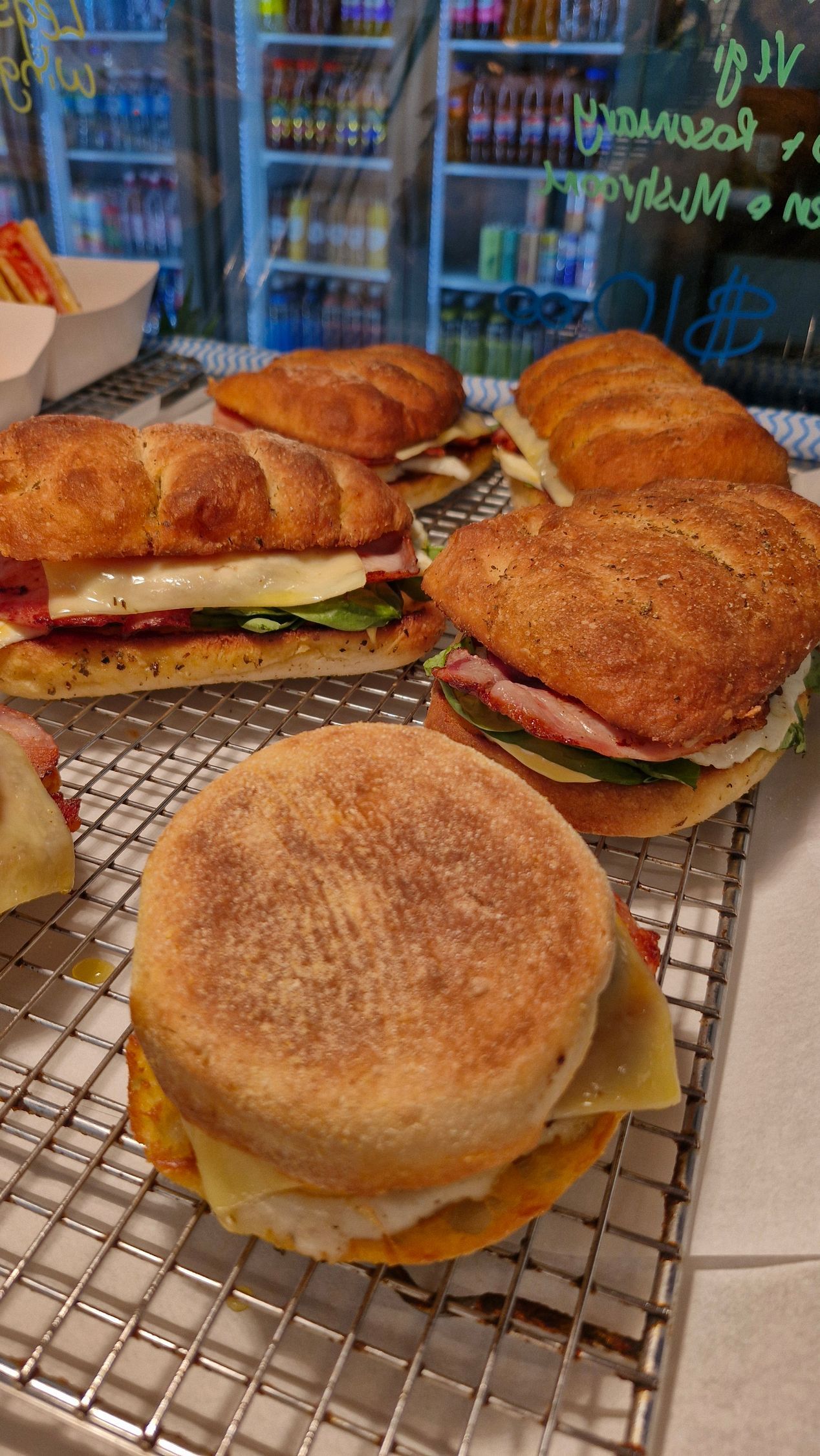 Sandwiches on a wire rack, displayed at a counter, inside a cafe setting.