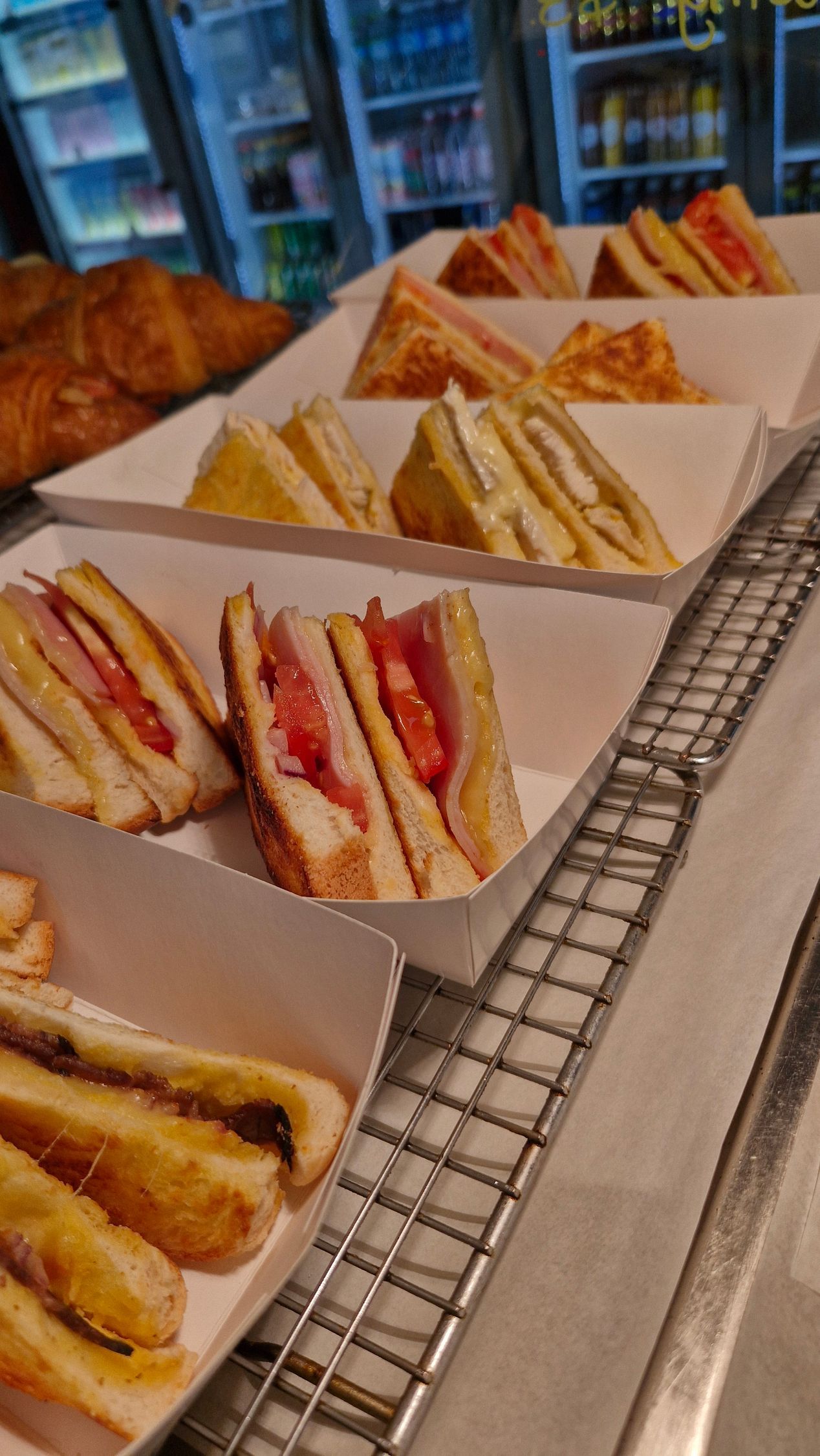 Sandwiches in white trays on a metal rack, various fillings visible. A food counter setting. — Boundary Street Fish & Burger Bar in Railway Estate, QLD