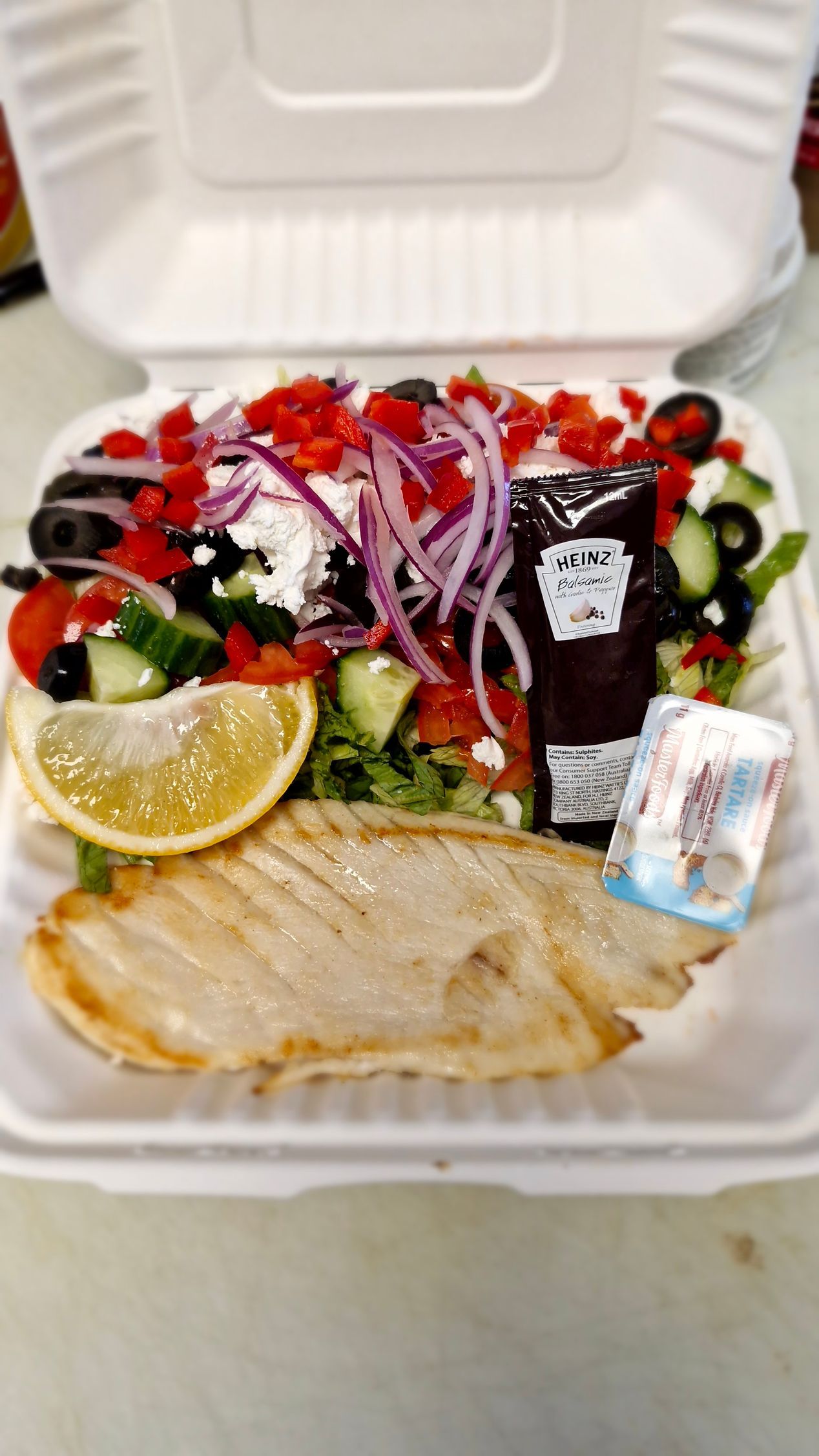 Greek salad with grilled protein, lemon wedge, and dressing in a take-out container. — Boundary Street Fish & Burger Bar in Railway Estate, QLD