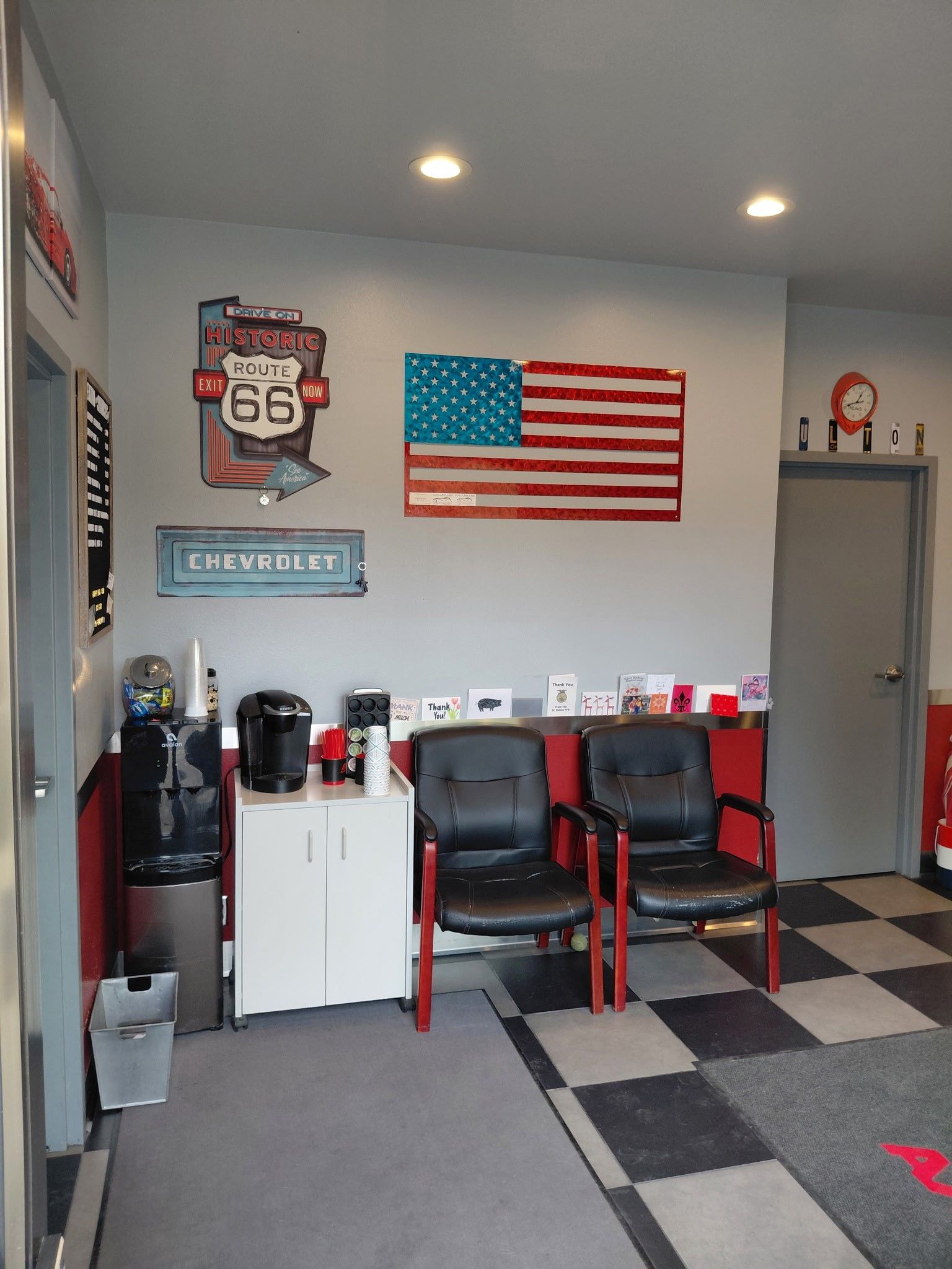 Waiting room with Route 66 and American flag art, chairs, and coffee station.
