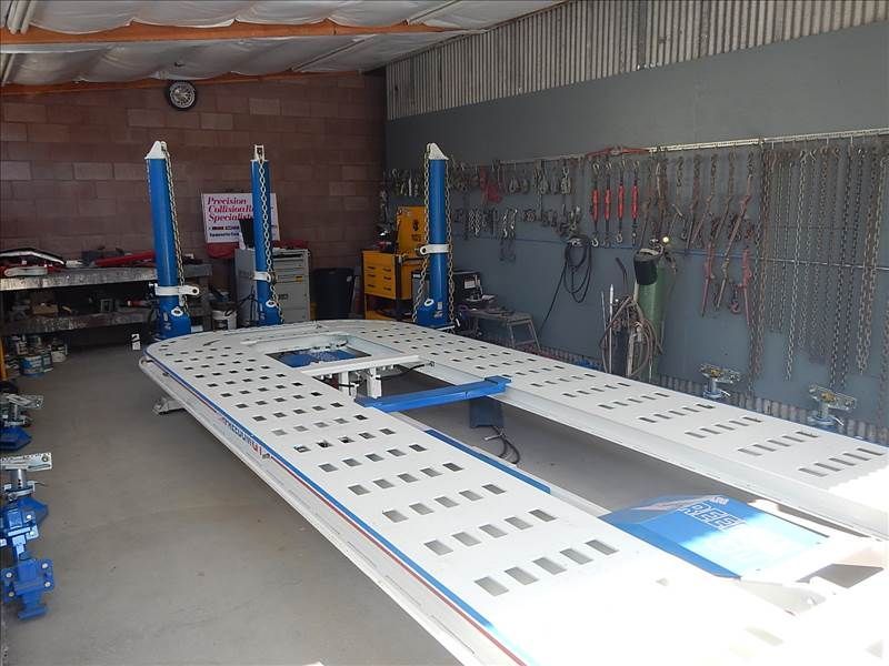 A car frame repair machine in a workshop, with chains and tools on the wall.