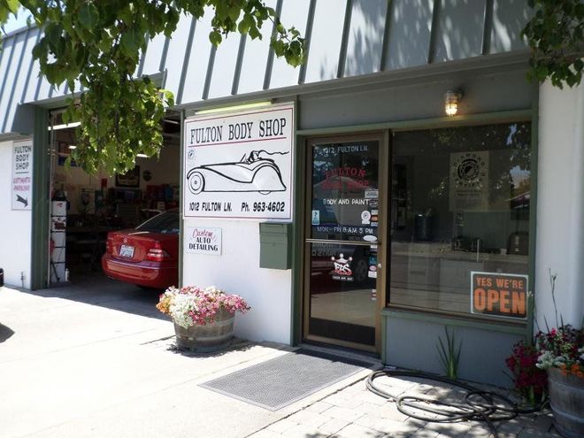 Auto repair shop exterior with open door and signage.