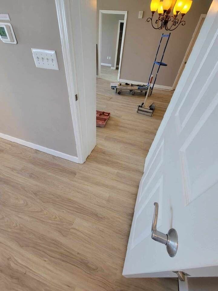 A door is open to a hallway with hardwood floors and a chandelier.