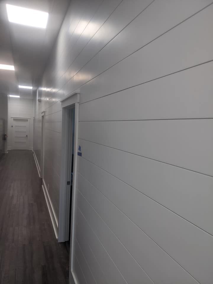 A long hallway with white walls and wooden floors.