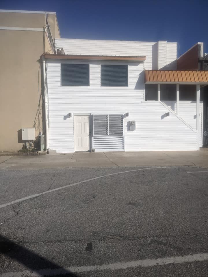 A white building with a brown roof is sitting on the side of the road.