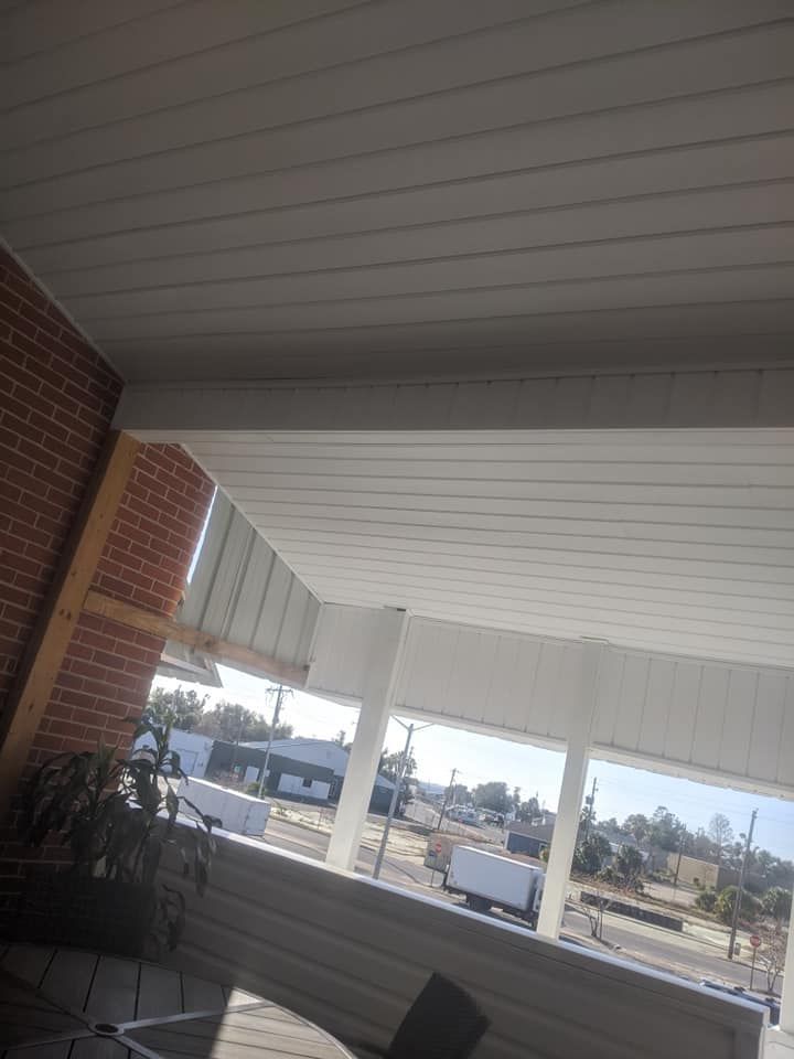 A porch with a white ceiling and a brick wall.