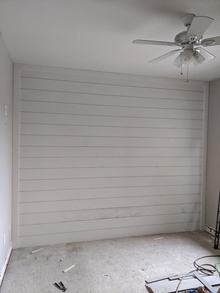 A room with a white wall and a ceiling fan.