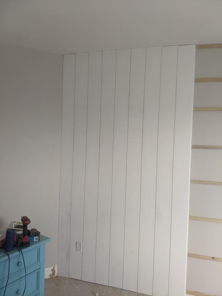 A room with a white wall and a blue dresser.