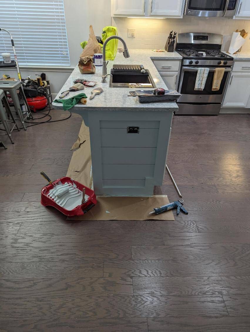 A kitchen island is being painted in a kitchen.