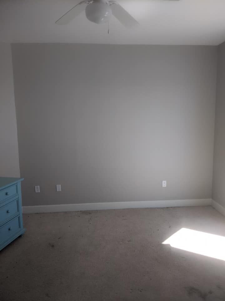 An empty bedroom with a ceiling fan and a blue dresser.