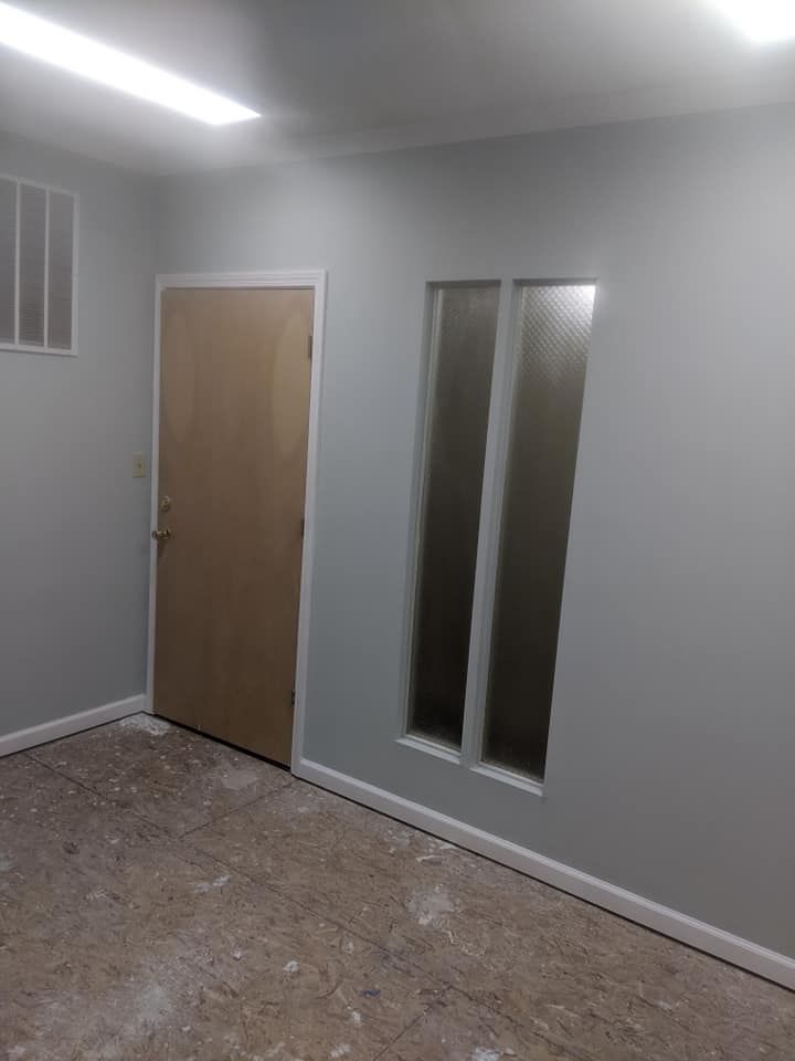 A room with a door and two windows in it.