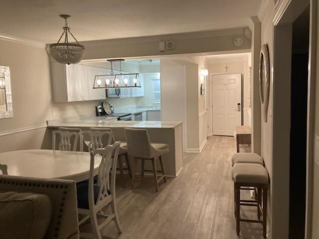 A dining room with a table and chairs and a kitchen in the background