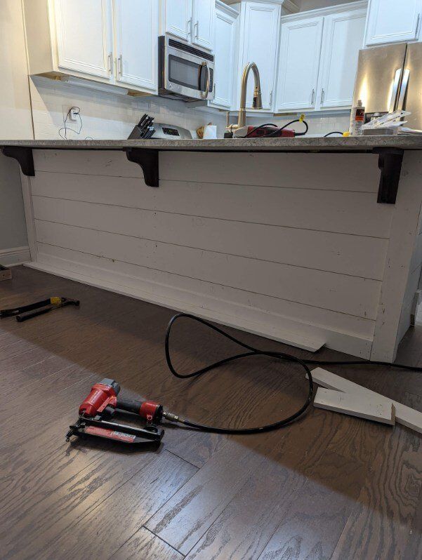 A kitchen island is being built and a stapler is laying on the floor.