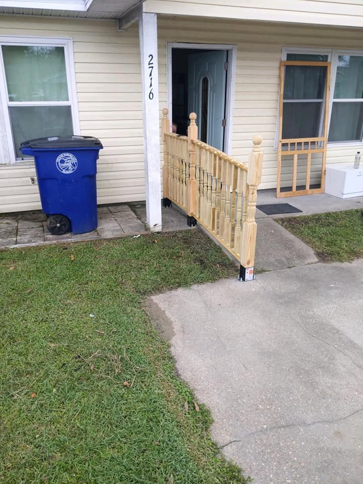 A blue trash can is sitting next to a wooden fence in front of a house.