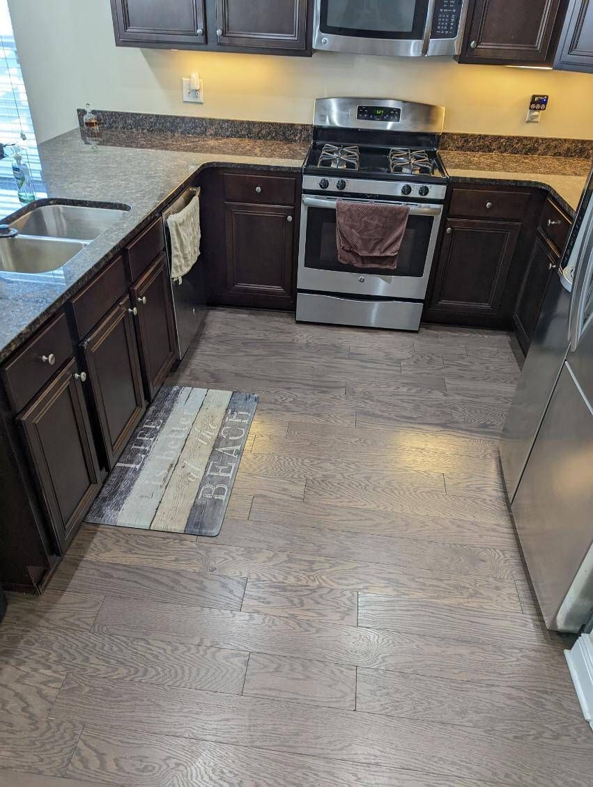 A kitchen with a stove , sink , refrigerator and microwave.