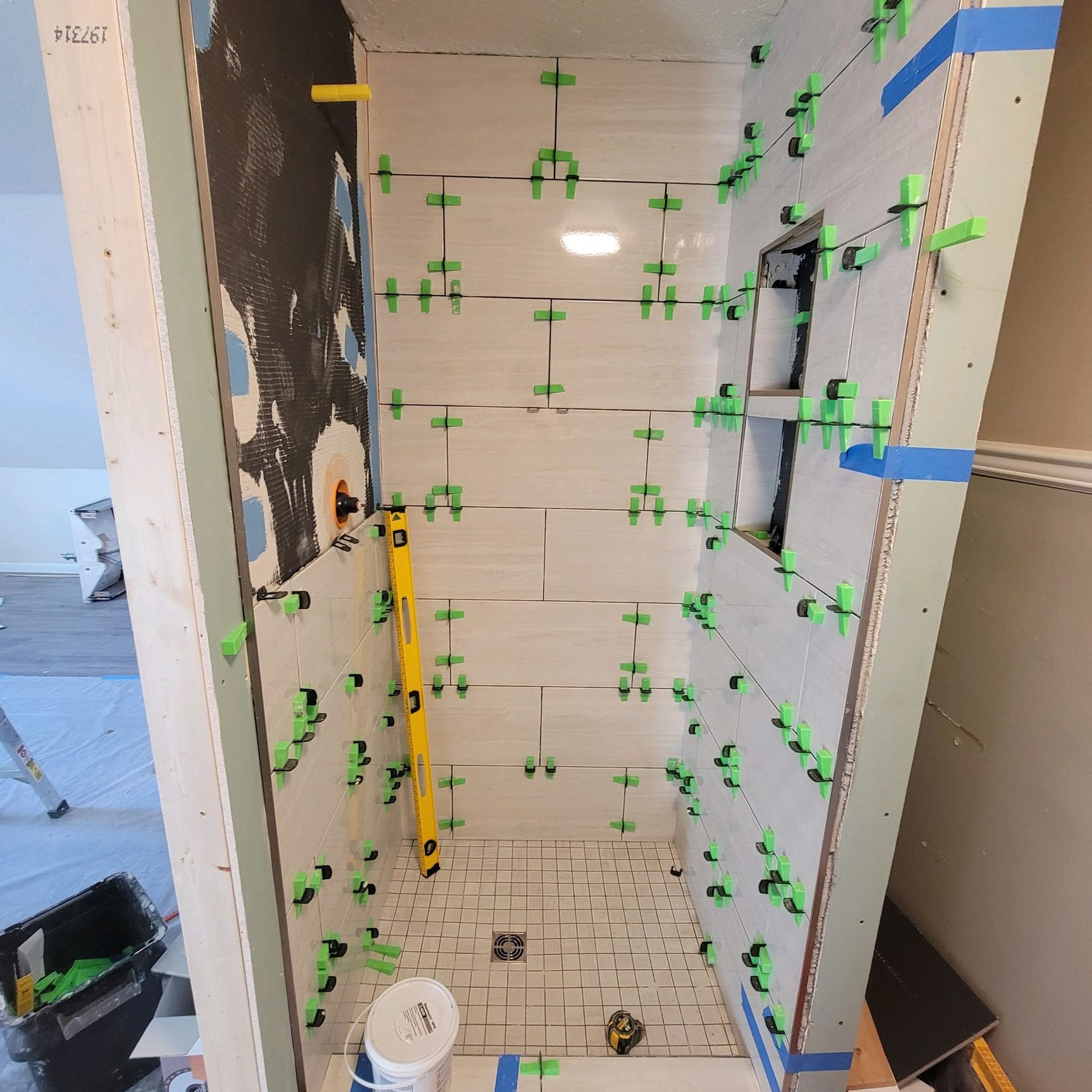 A bathroom under construction with tiles and a yellow level.