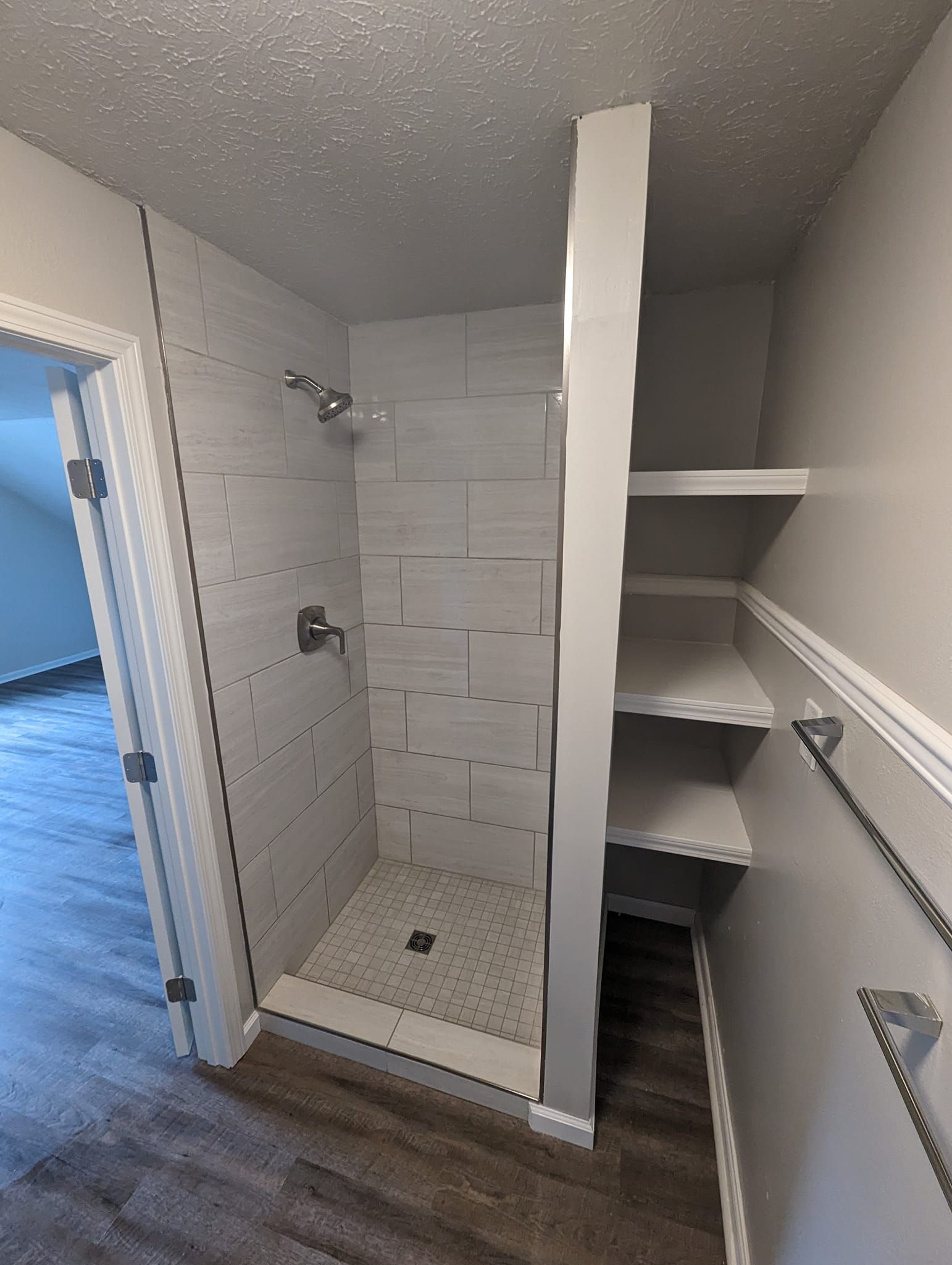 A bathroom with a walk in shower and shelves.