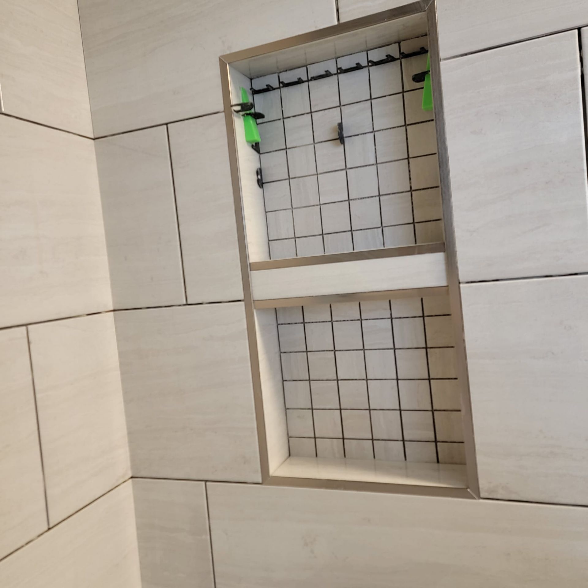 A bathroom with white tiles and a shelf in the corner