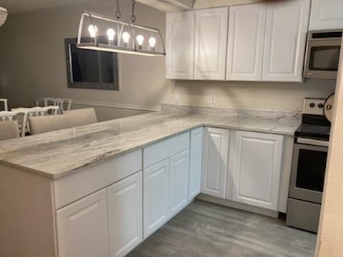 A kitchen with white cabinets , granite counter tops , stainless steel appliances , and a large island.