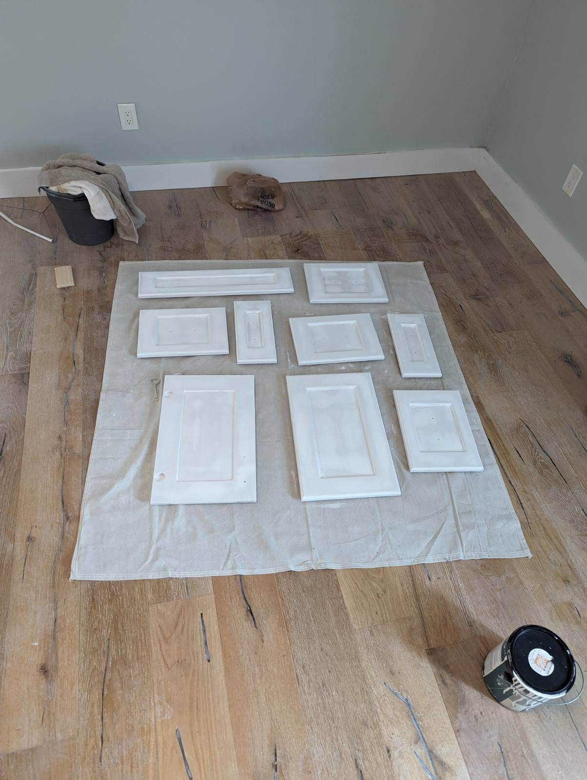 A bunch of white cabinet doors are sitting on a wooden floor.