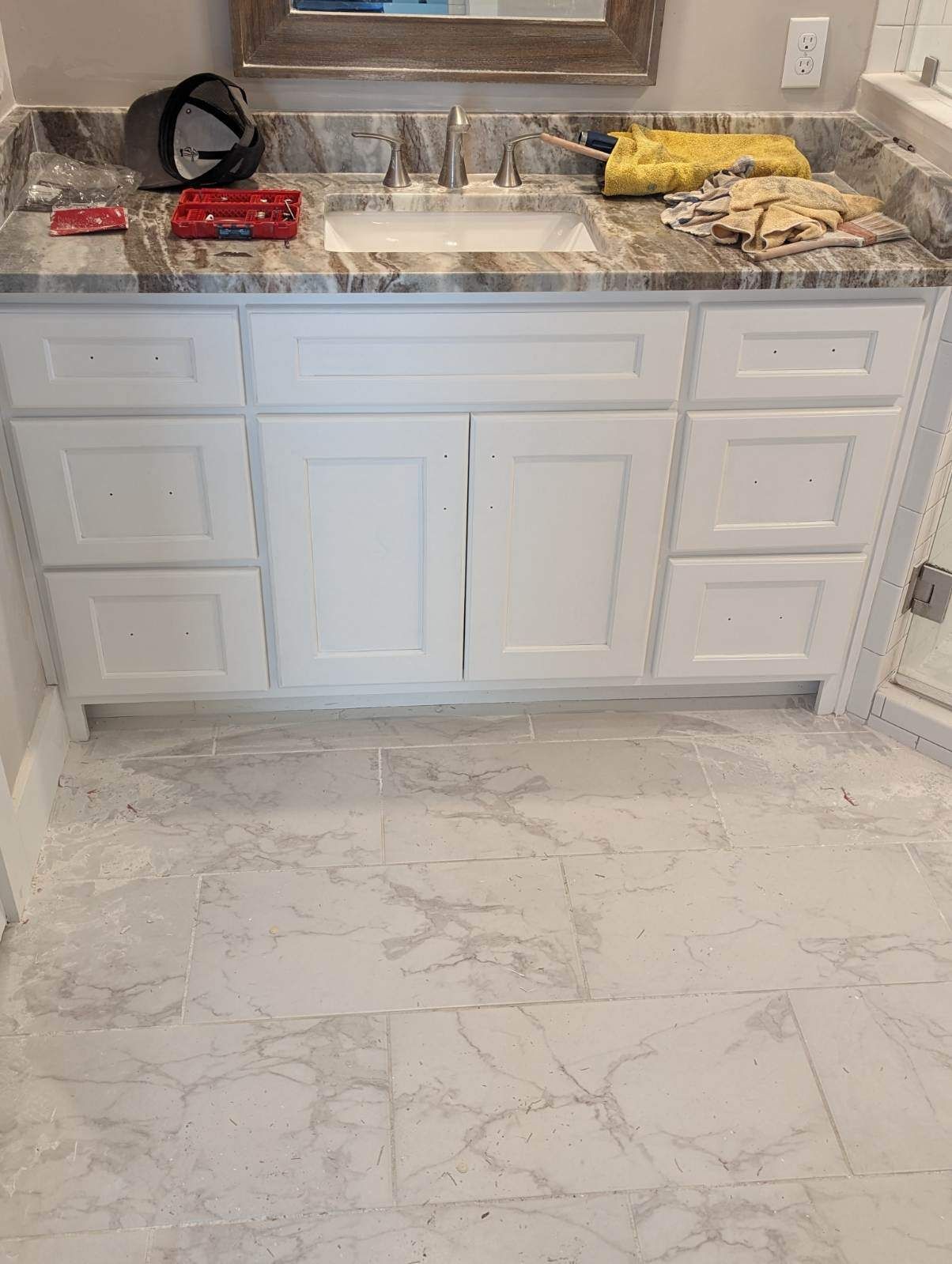 A bathroom vanity with a sink and marble counter top.