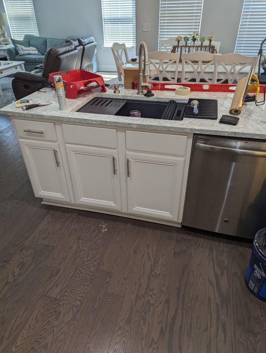 A kitchen with white cabinets , a sink , and a stainless steel dishwasher.