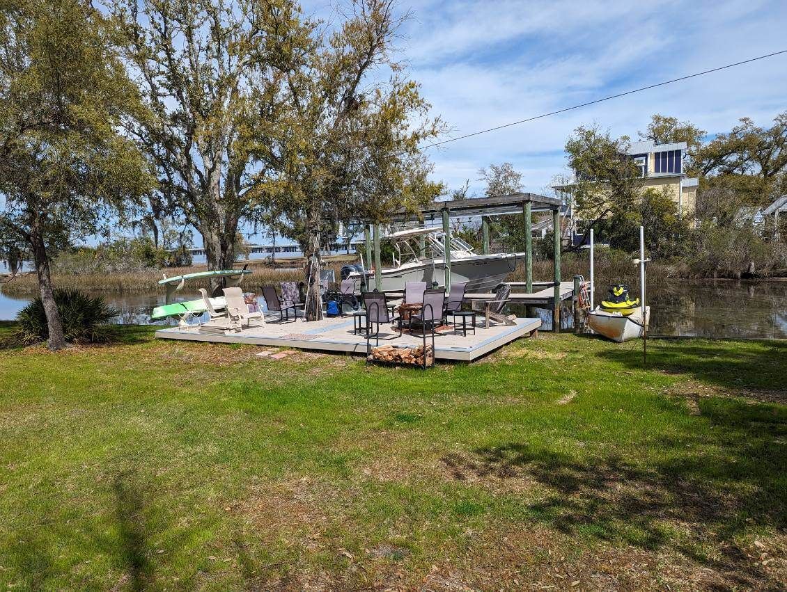A dock with chairs and tables next to a body of water.