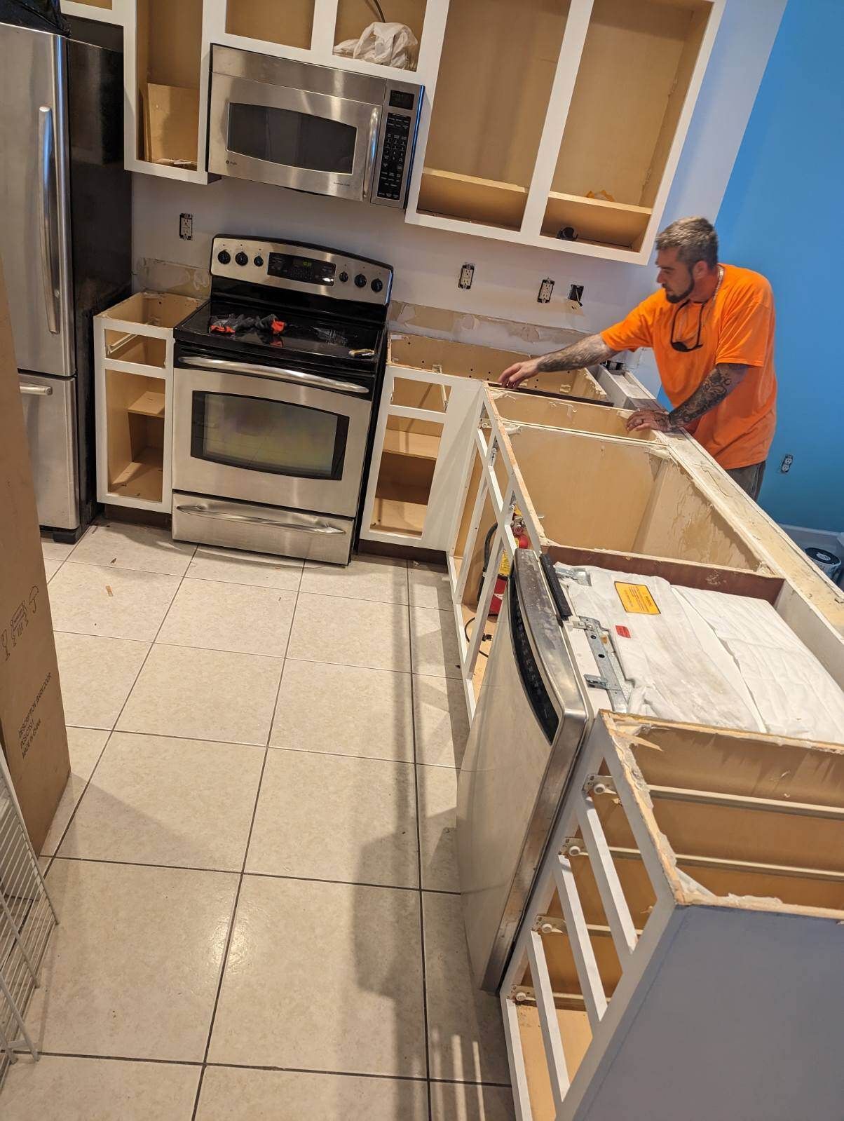 A man in an orange shirt is working in a kitchen