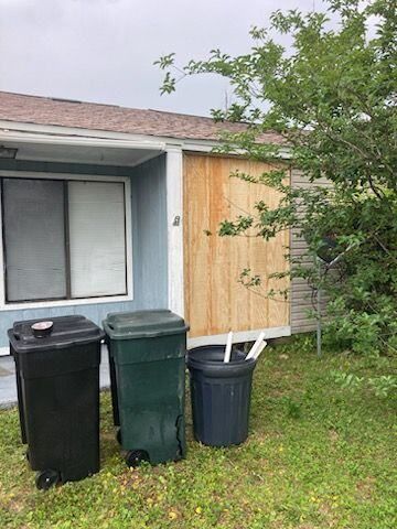 Three trash cans are sitting in front of a house.