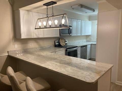 A kitchen with white cabinets , granite counter tops , stainless steel appliances and a clock on the counter.
