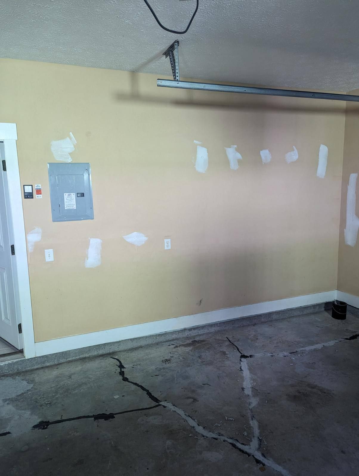 An empty room with a door and a light switch on the wall.