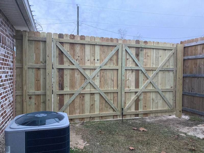 A wooden fence with a gate and an air conditioner in the backyard of a house.