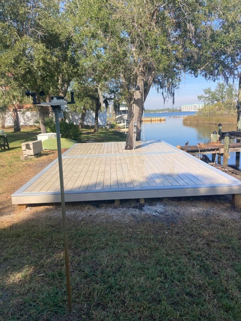A wooden dock is sitting next to a body of water surrounded by trees.