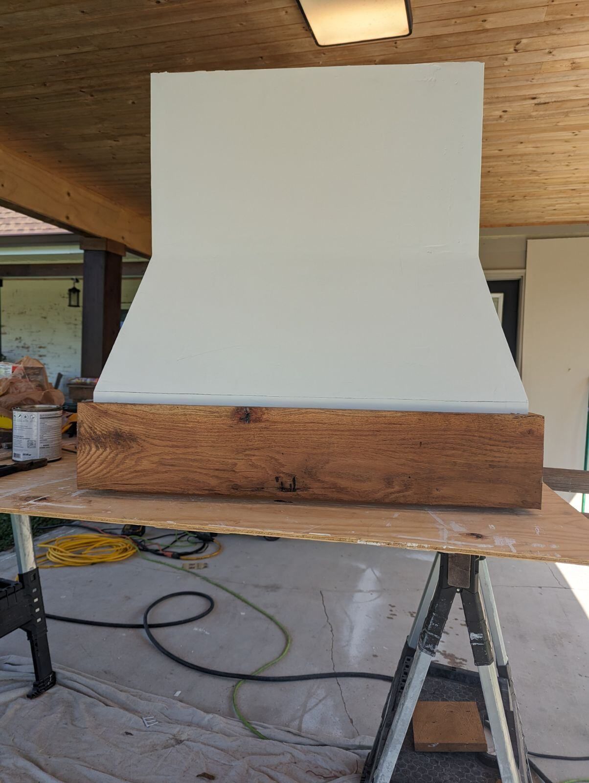 A white hood with a wooden base is sitting on top of a wooden table.