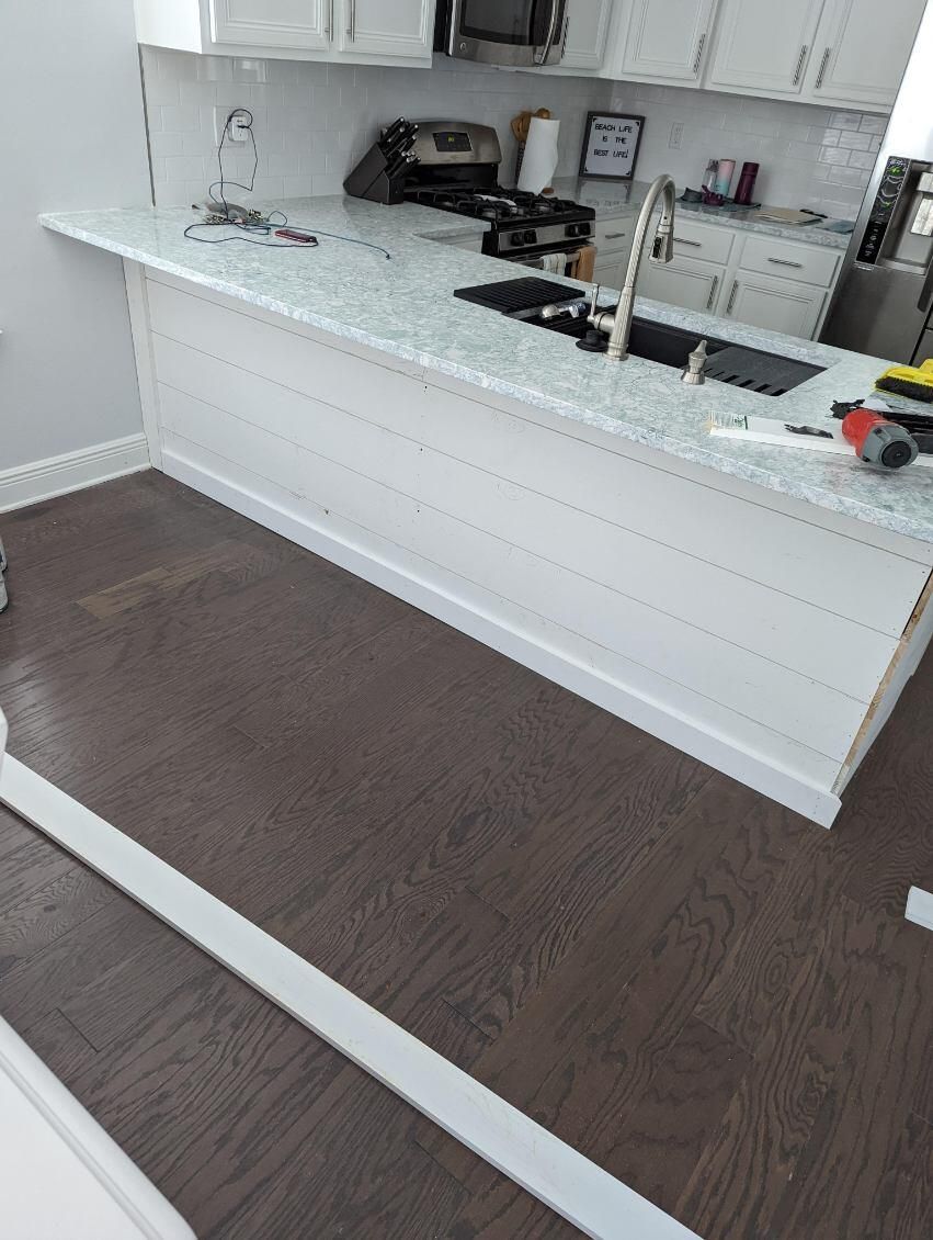 A kitchen with white cabinets , a sink , and a stove.