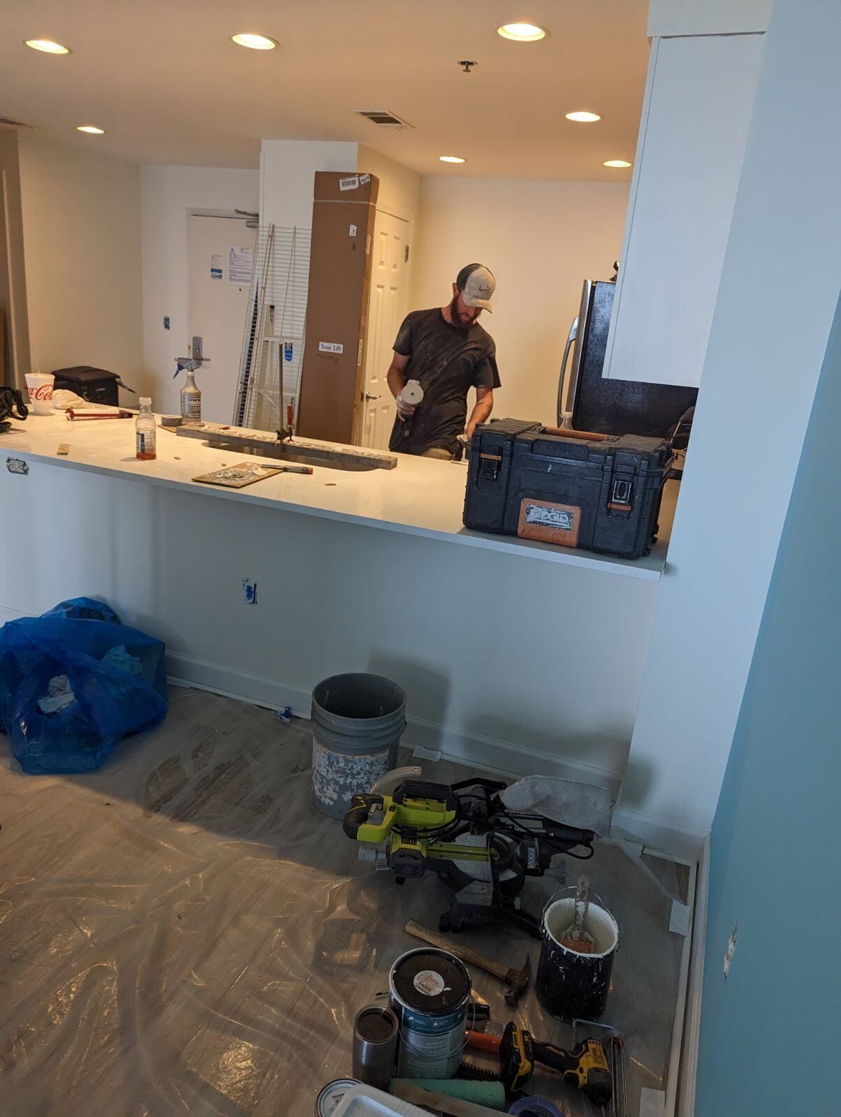 A man is standing in a kitchen working on a counter.
