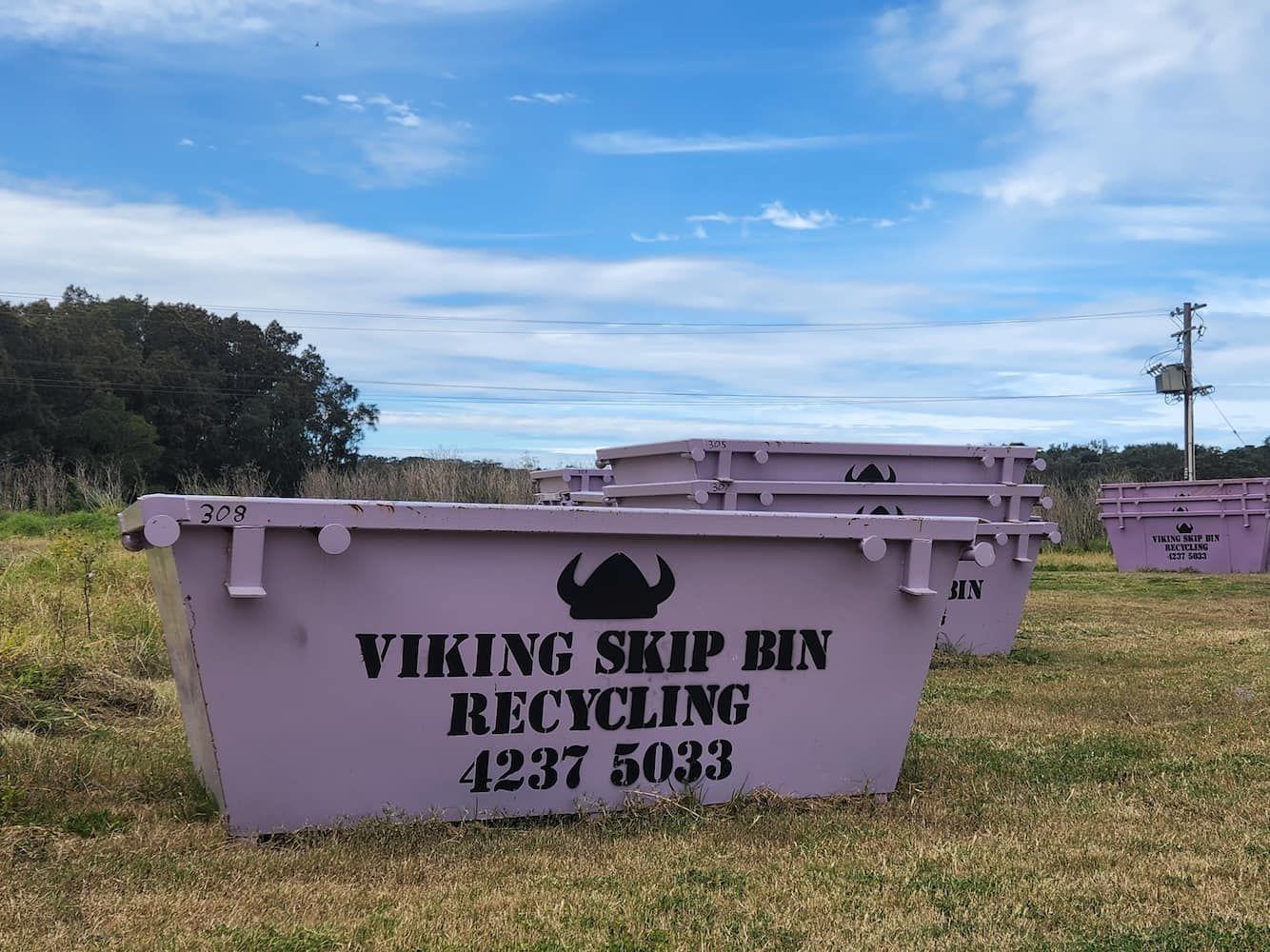 A Purple Viking Skip Bin is Sitting in a Grassy Field — Viking Skip Bin Recycling In Dunmore, NSW