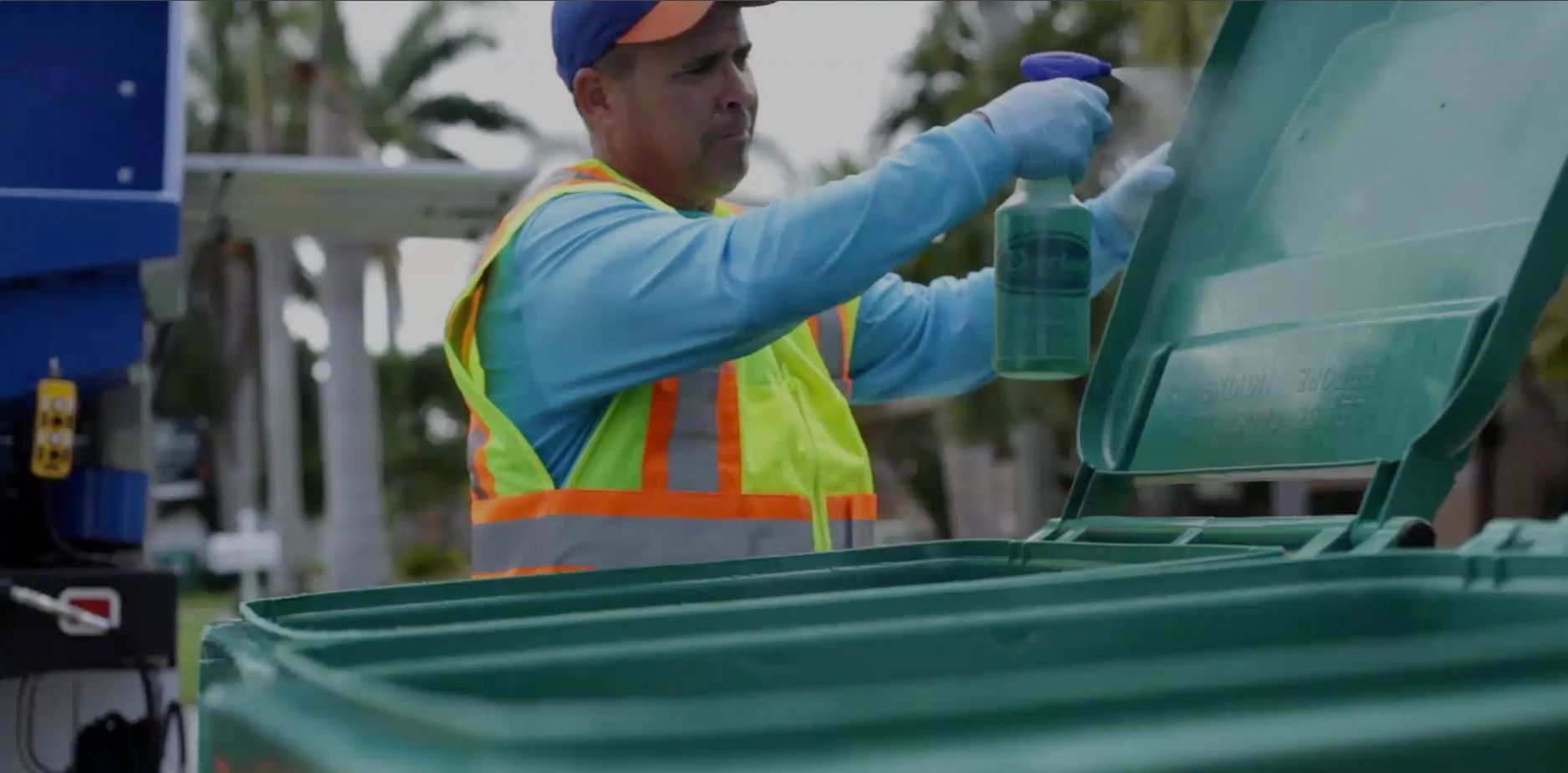 A man is cleaning a trash can with a spray bottle.