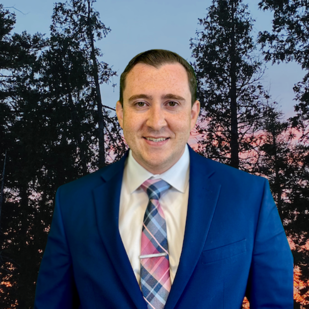 A man in a suit and tie is smiling for the camera