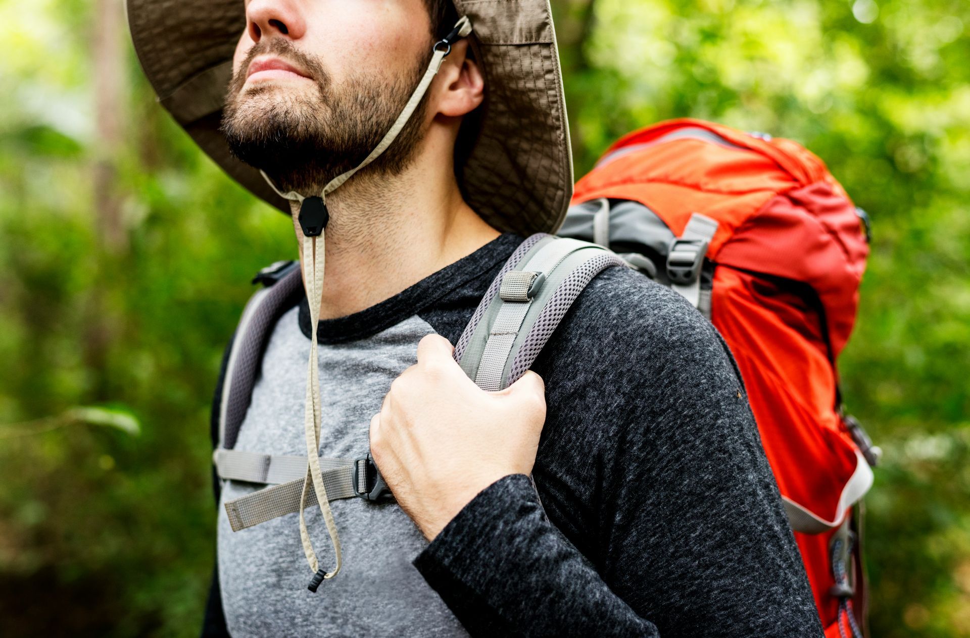 A man with a backpack is standing next to a lake in the woods.