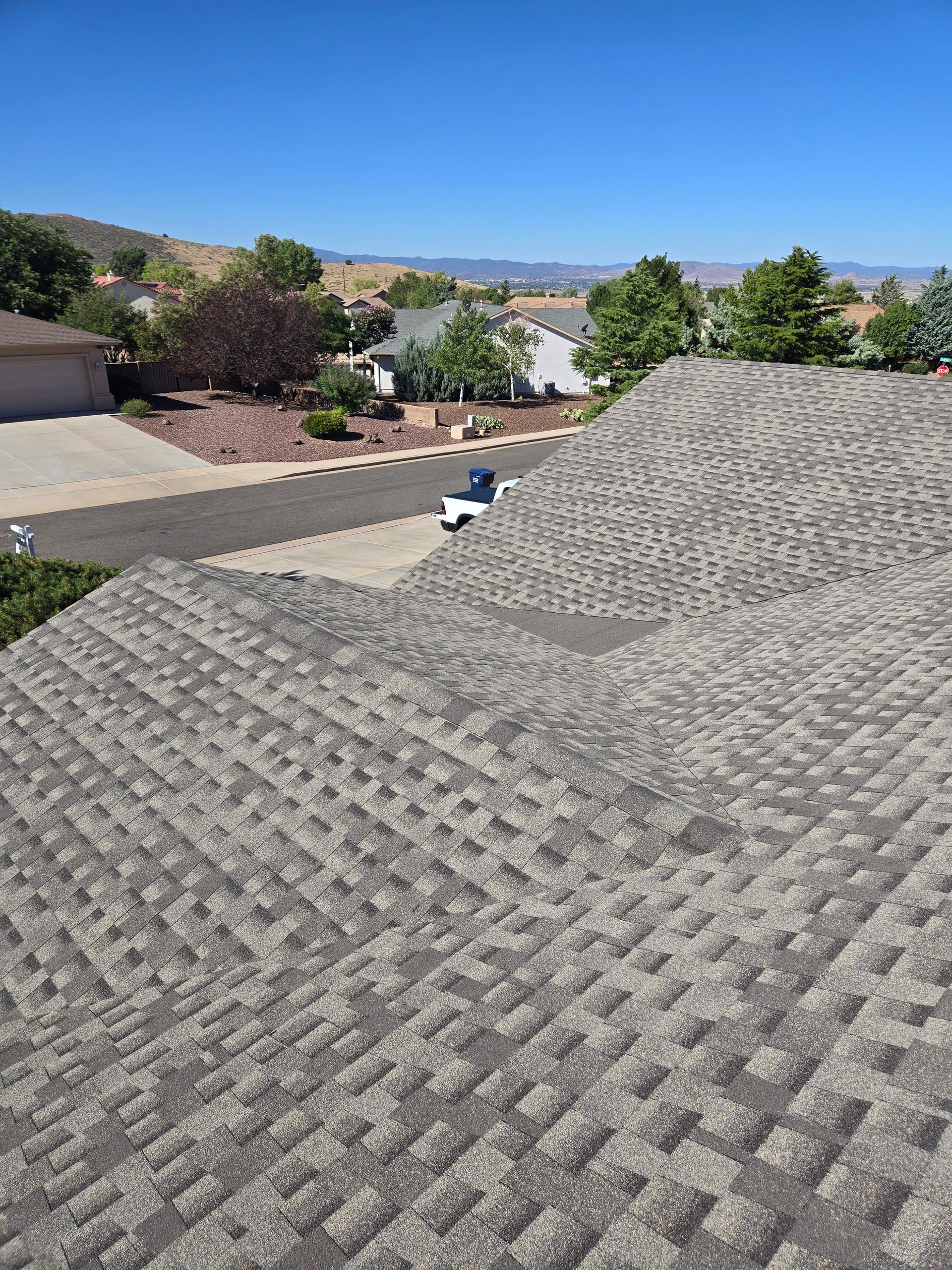 Overhead view of a house with a gray shingled roof, unfinished exterior, and an open garage.