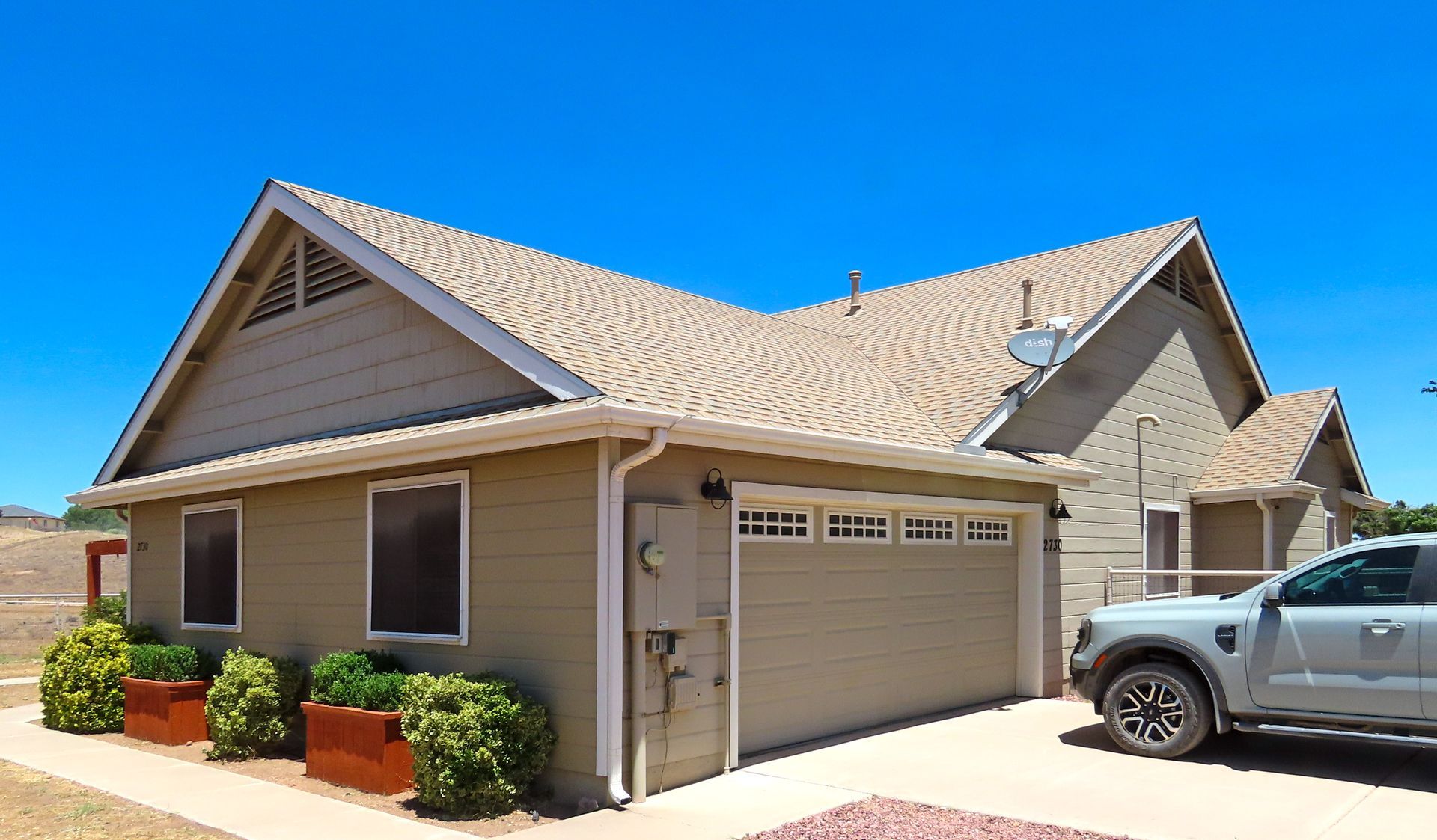 Single-story beige house with a two-car garage and a parked pickup truck in the driveway