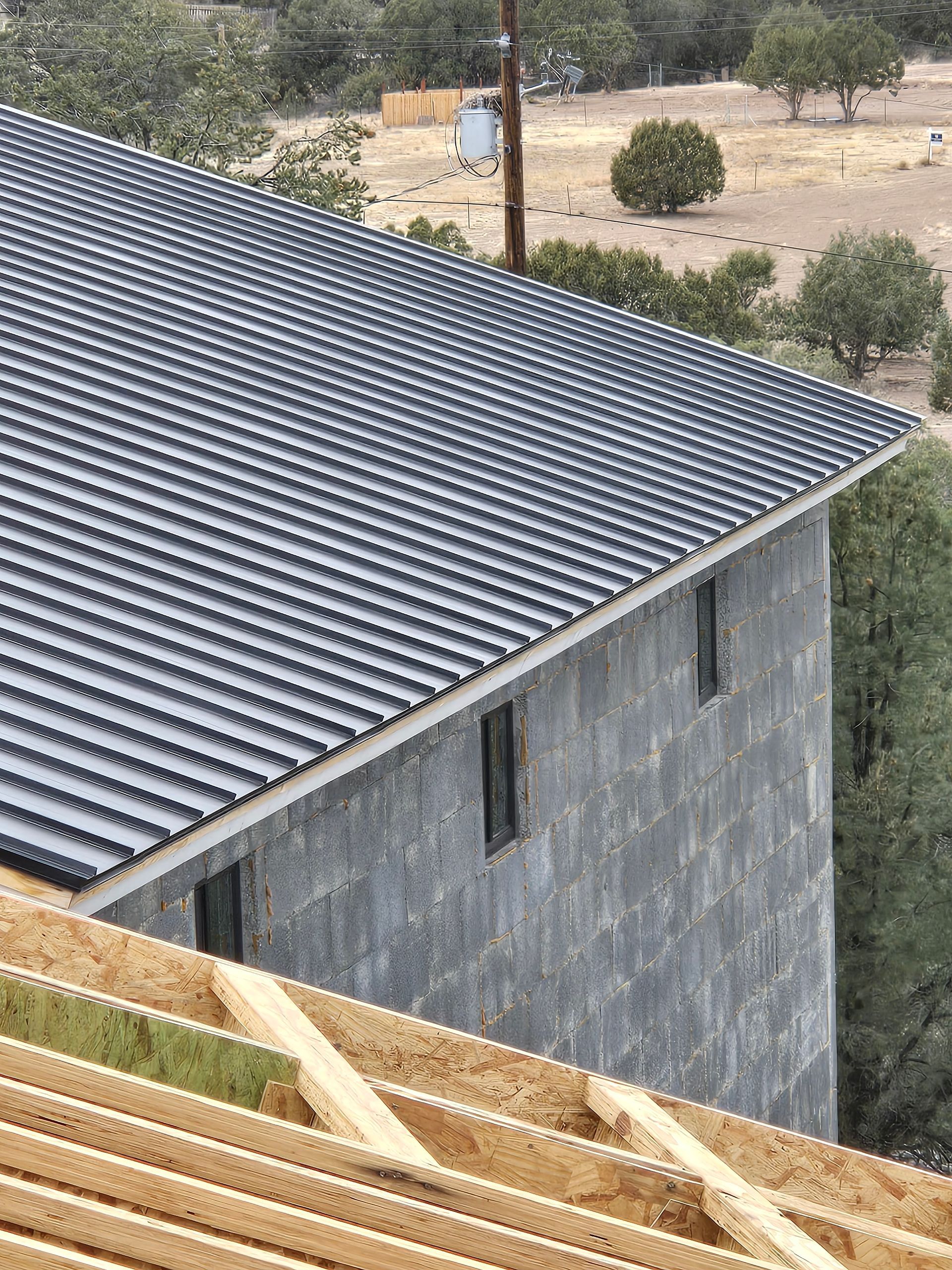 Building under construction with a corrugated metal roof, framing visible below.