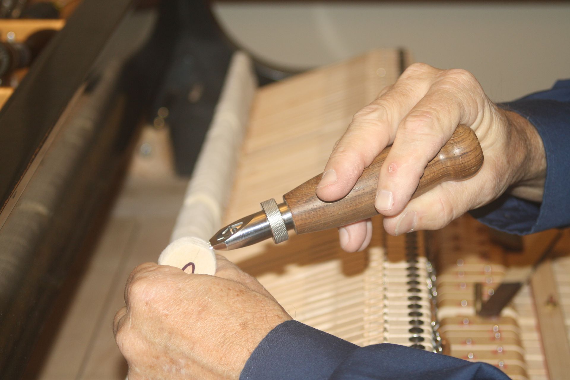 A person is working on a piano with a tool.