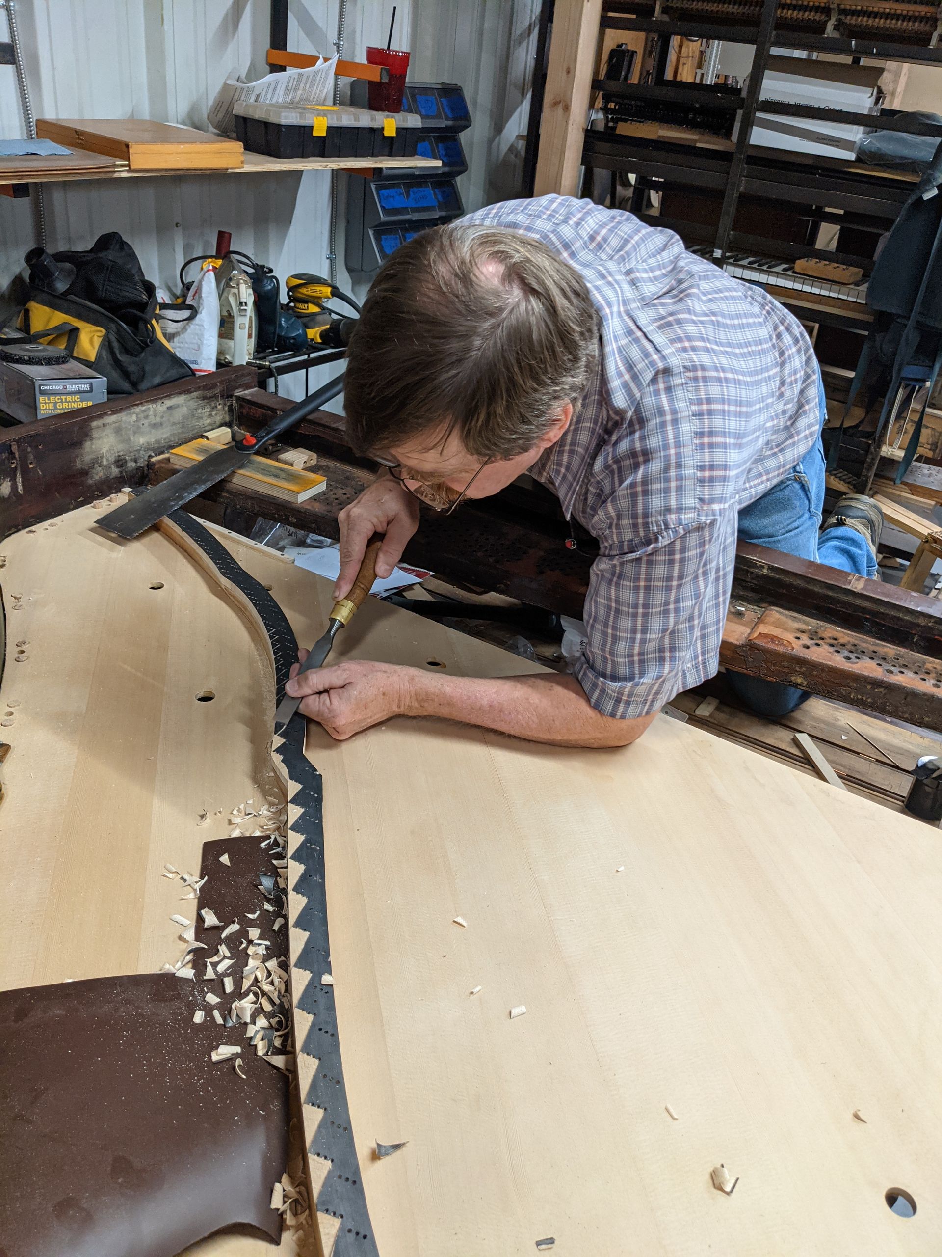 A man is working on a piece of wood in a workshop.