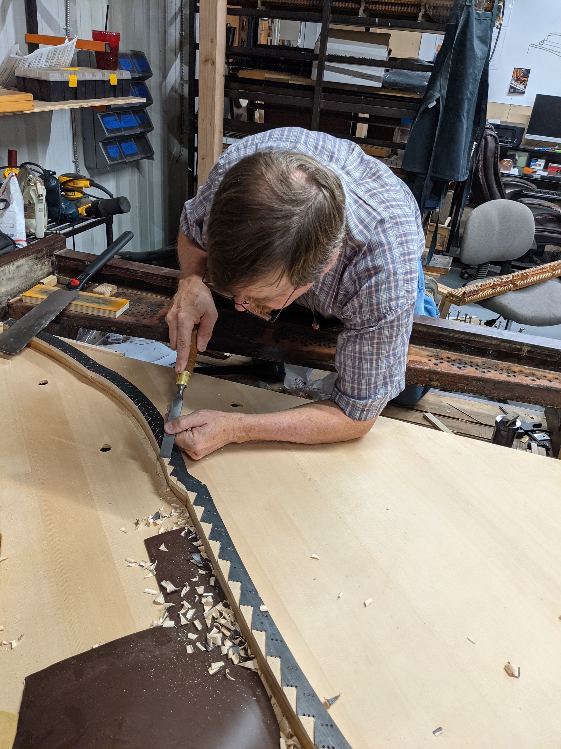 A man is working on a piece of wood in a workshop.