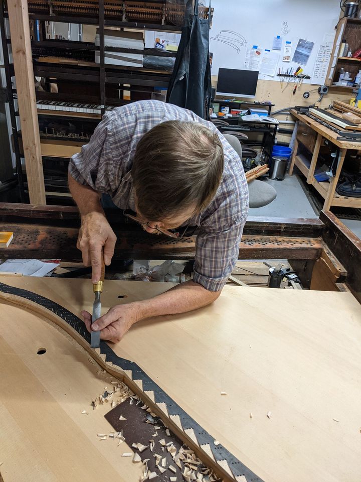 A man is working on a piece of wood in a workshop.