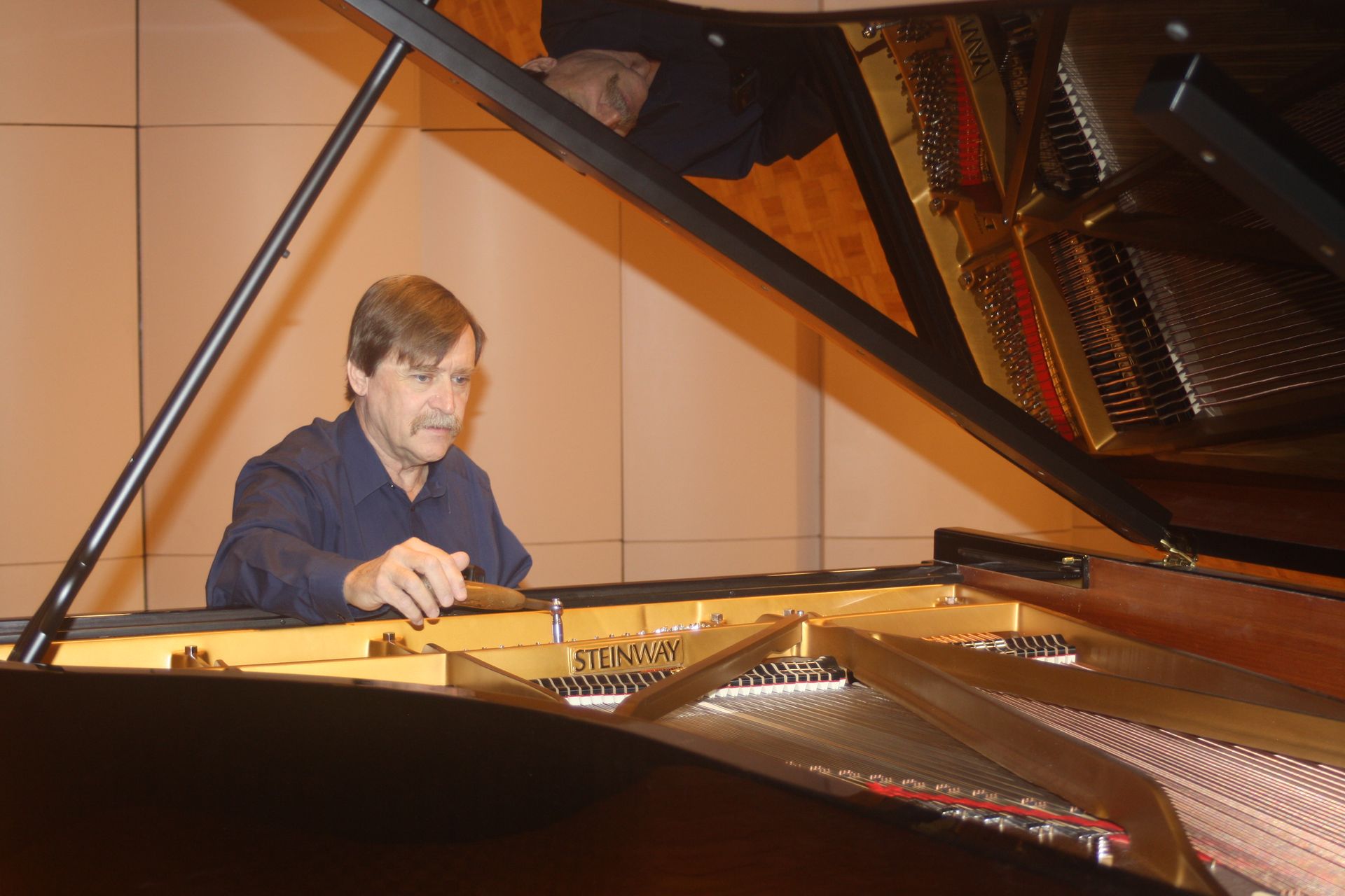 A man is playing a piano with the lid open