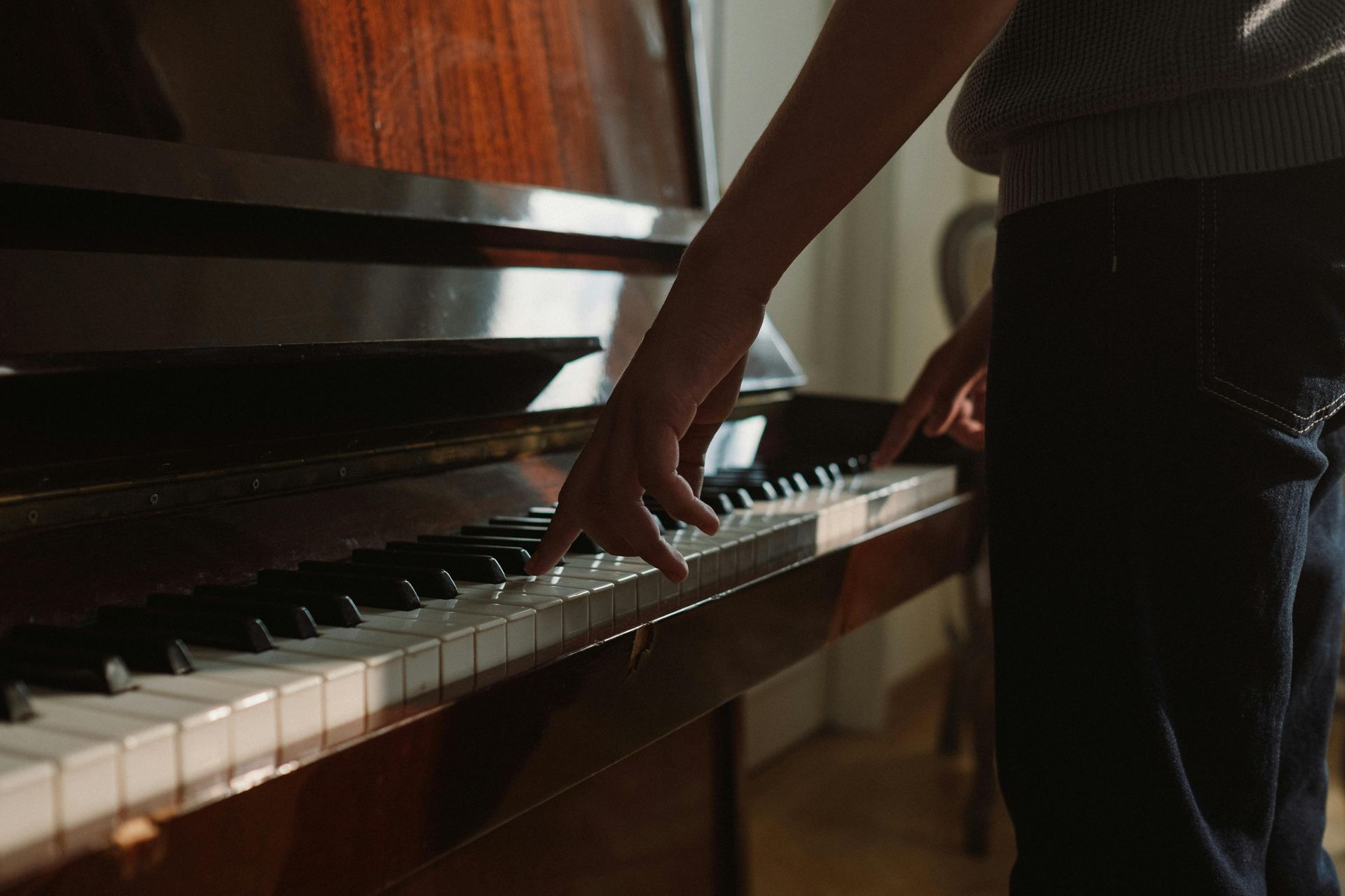 A person is playing a piano with their hands on the keys.